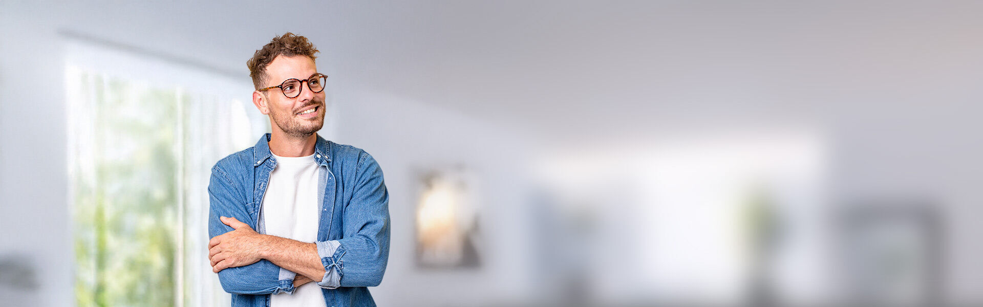 ein Mann in einem blauen Hemd mit Brille lächelt und blickt nach links