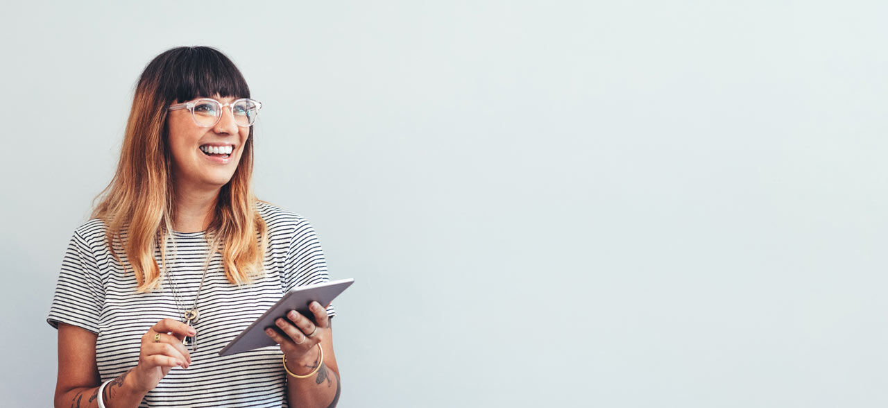 eine Frau in der Brille hält eine Tablet und lächelt